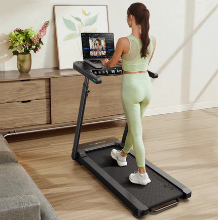 用英语描述这张图片，字符在80以内 Preview  A woman in light green workout attire using a treadmill with a screen displaying multiple video options.