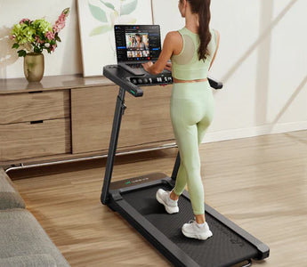 A woman in light green workout attire using a treadmill with a tablet stand in a modern living room.