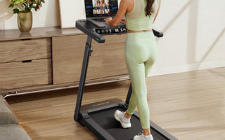 A woman uses a treadmill with a laptop, exercising while working.