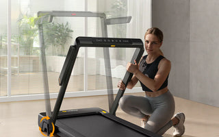 A woman is kneeling next to a UREVO Strol 1 Pro treadmill, demonstrating its easy storage feature in a modern living space.