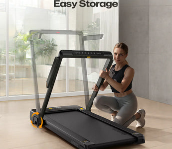 A woman is kneeling next to a UREVO Strol 1 Pro treadmill, demonstrating its easy storage feature in a modern living space.