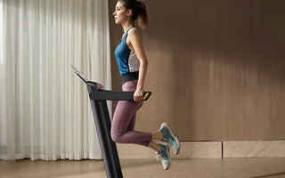 A woman in blue and pink athletic wear is running on a treadmill in a room with curtains.