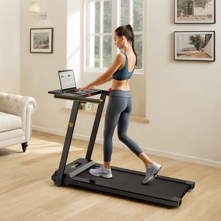 Woman walking on a treadmill while using a laptop in a home setting.